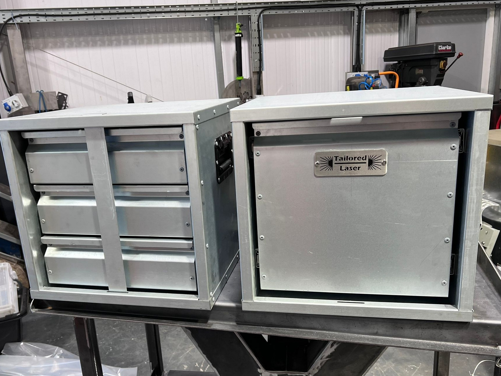Two custom metal van storage units with drawers and Tailored Laser branded panel on a workshop bench