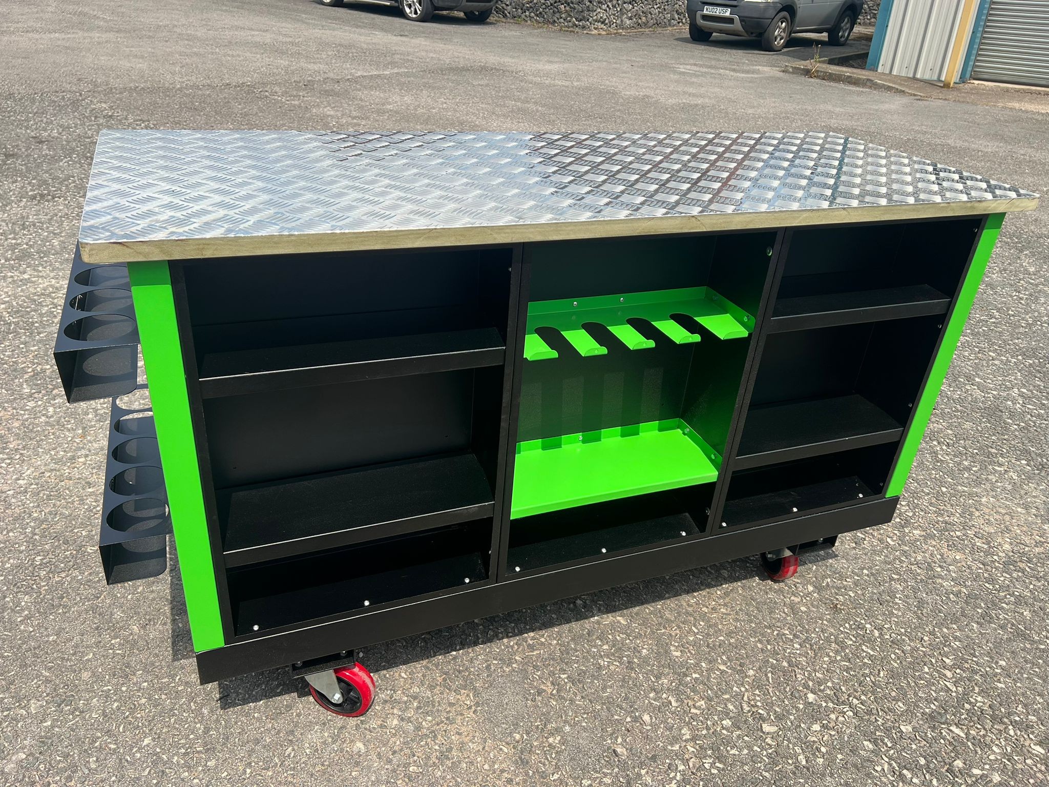 Custom green and black workshop unit with diamond‑plate top and mobile caster wheels