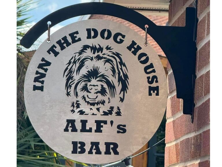Round metal bar sign with dog illustration and Inn The Dog House Alf’s Bar text