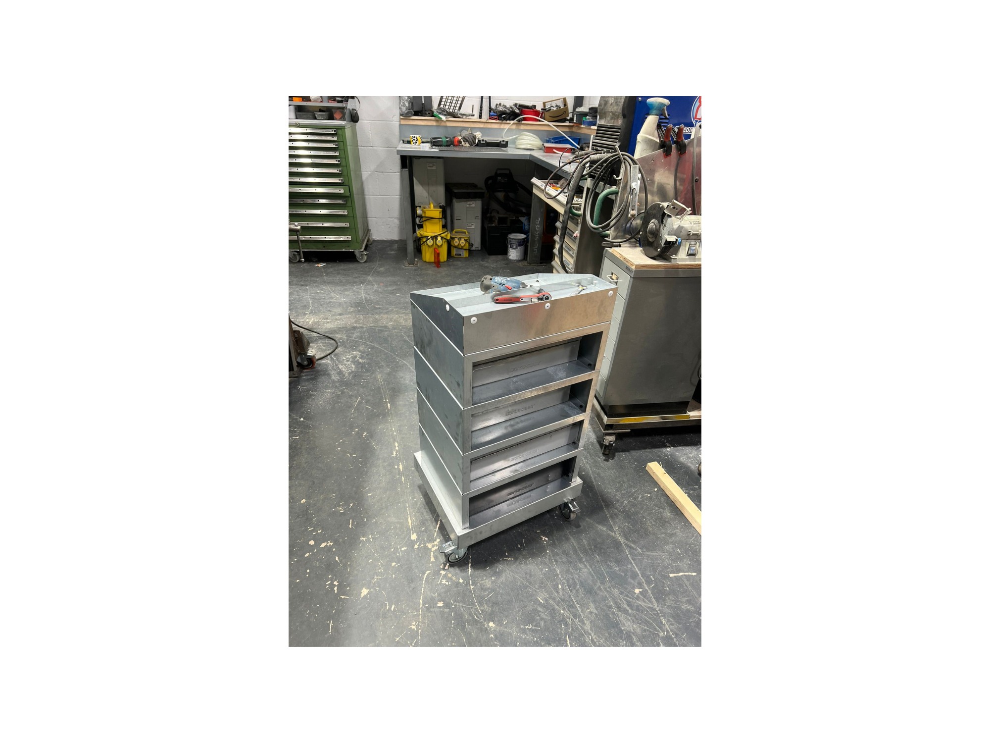Two custom metal van storage units with drawers and Tailored Laser branding on a workshop bench
