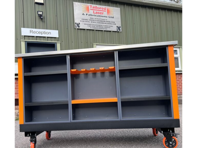 Large grey and orange workshop unit with stainless steel top and open shelves outside Tailored Laser